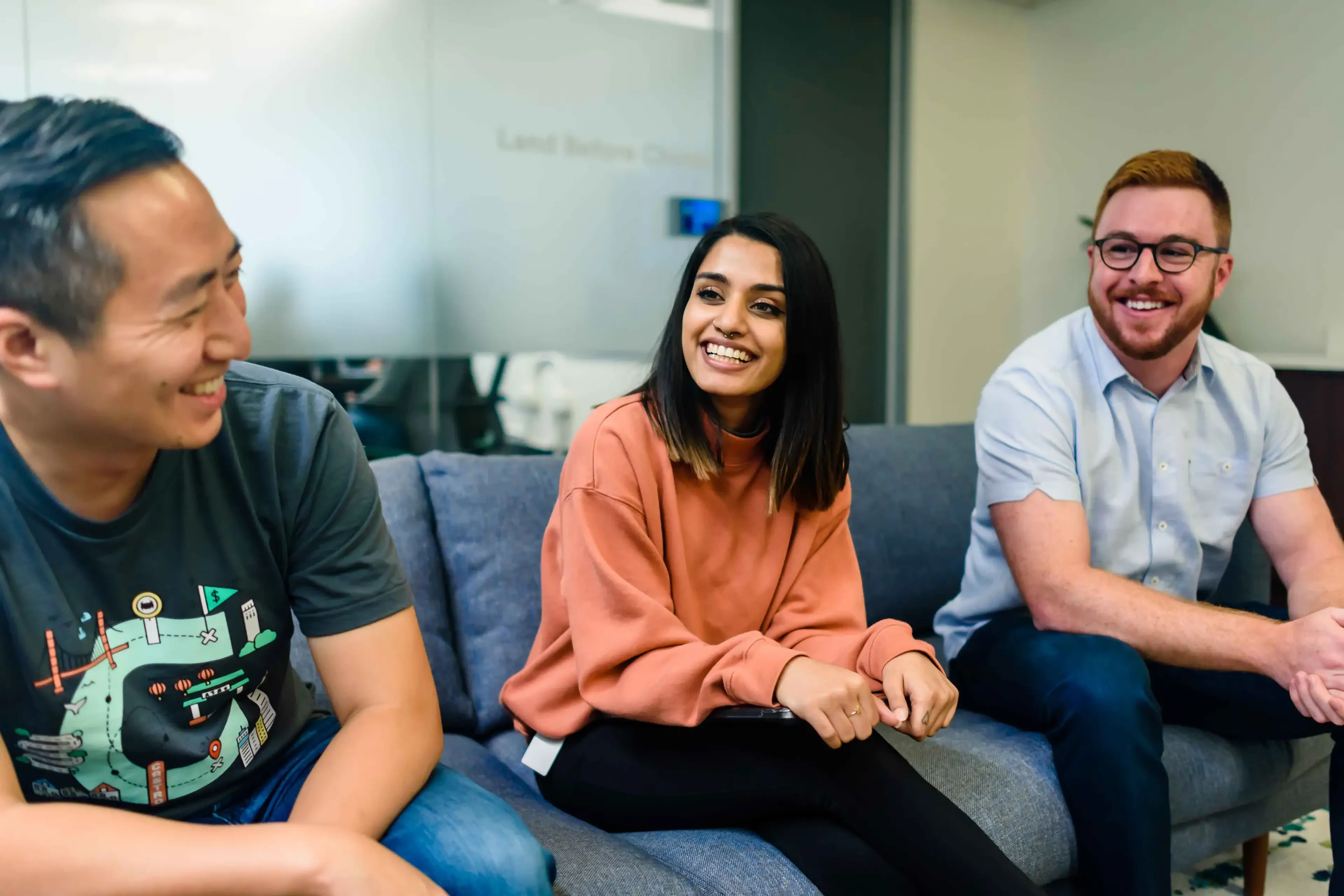 A group of people sitting on a couch smiling while having a conversation