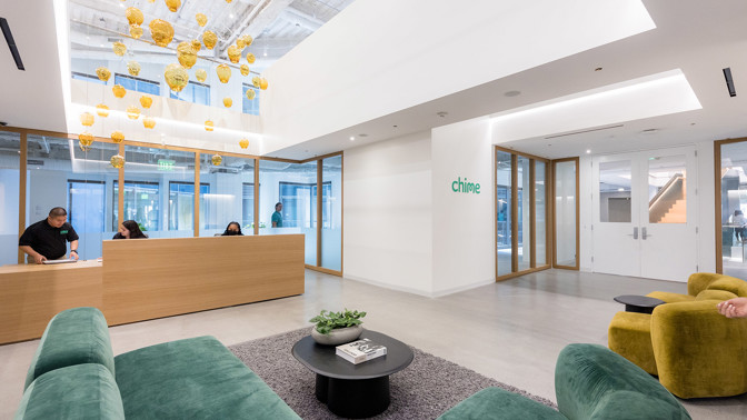 a lobby with green couches and a table